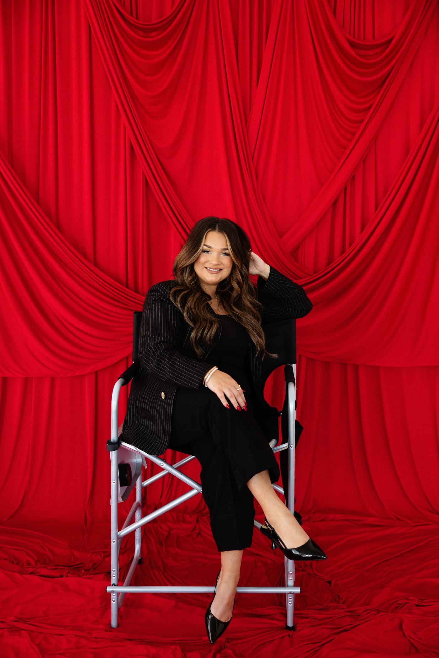 Chloe Wilson, seated against a deep red curtain backdrop