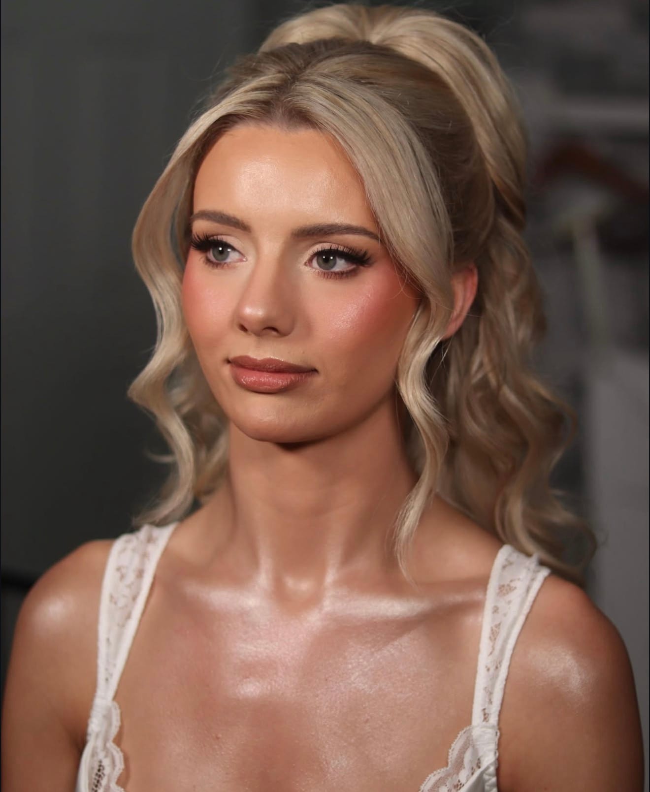 Bride with soft glam makeup, a glossy nude lip and a high blonde ponytail