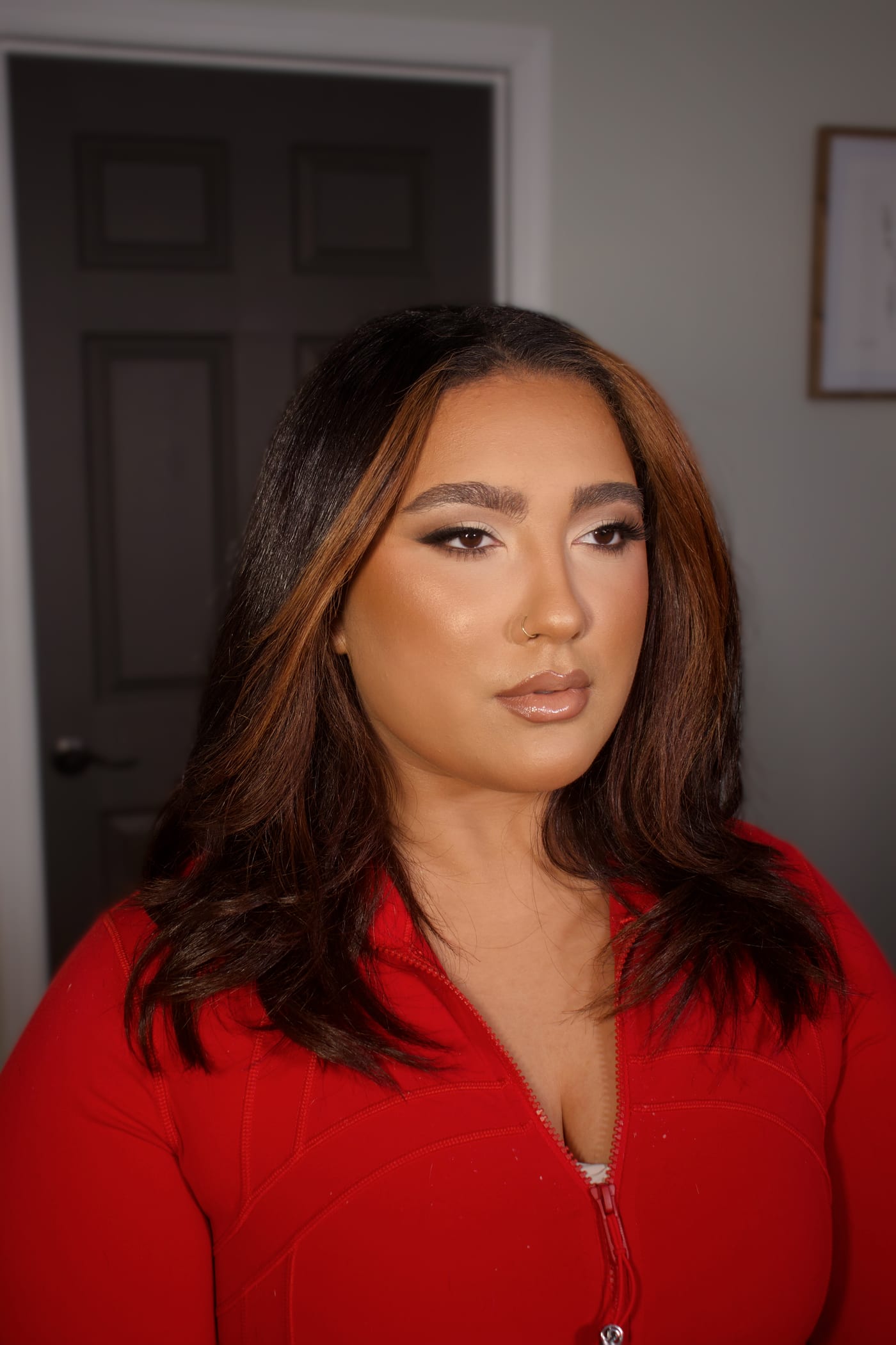 Editorial look with a warm bronze eye and a deep red lip against a red backdrop